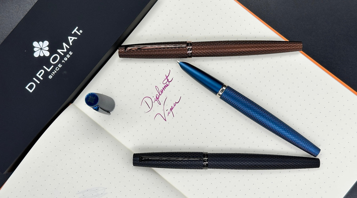 Diplomat Viper fountain pens in black, blue, and brown displayed together on dark background