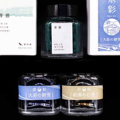 An overhead view of 3 Kyoto ink bottles and 2 of their boxes by their sides.