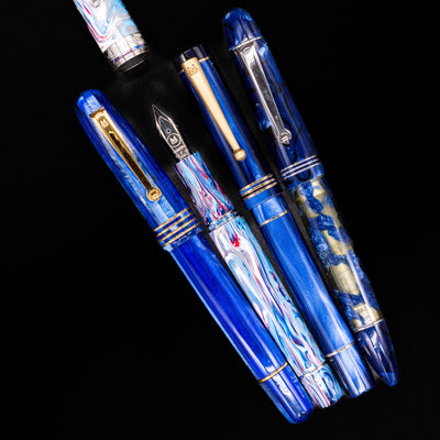 An overhead view of 4 Molteni fountain pens in different colors, 3 capped and 1 uncapped showcasing its silvr nib.