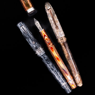 An overhead view of 3 different Omas fountain pens with 2 pens capped and 1 uncapped showcasing its silver nib