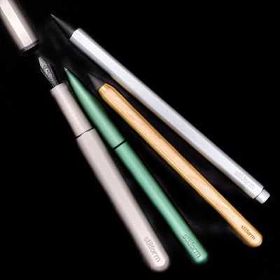 An overhead view of 4 stilform writing utensils; a fountain pen, ballpoint pen, rollerball pen and a pencil.