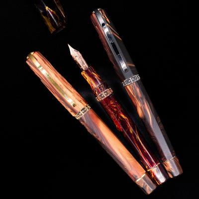 An overhead view of 3 Visconti homo sapiens foutain pens, 2 capped and 1 uncapped showcasing its gold nib.