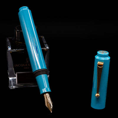 AP Limited Editions Proplyd Aqua Fountain Pen leaning on an ink bottle uncapped showcasing the detailing on the nib.