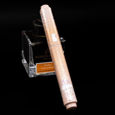 AP Limited Editions Sakura Lacquer Art Fountain Pen - Rabbits in a Summer Garden capped, leaning against an ink bottle. 