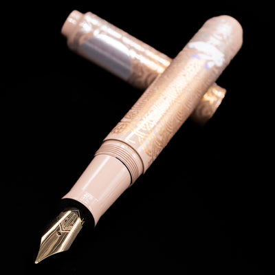 AP Limited Editions Sakura Lacquer Art Fountain Pen - Rabbits in a Summer Garden laying across its own cap, crossed, with a focus on the nib.