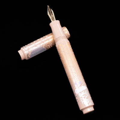 AP Limited Editions Sakura Lacquer Art Fountain Pen - Rabbits in a Summer Garden laying on top of its cap in a crossed position showing full view of the entire uncapped pen.