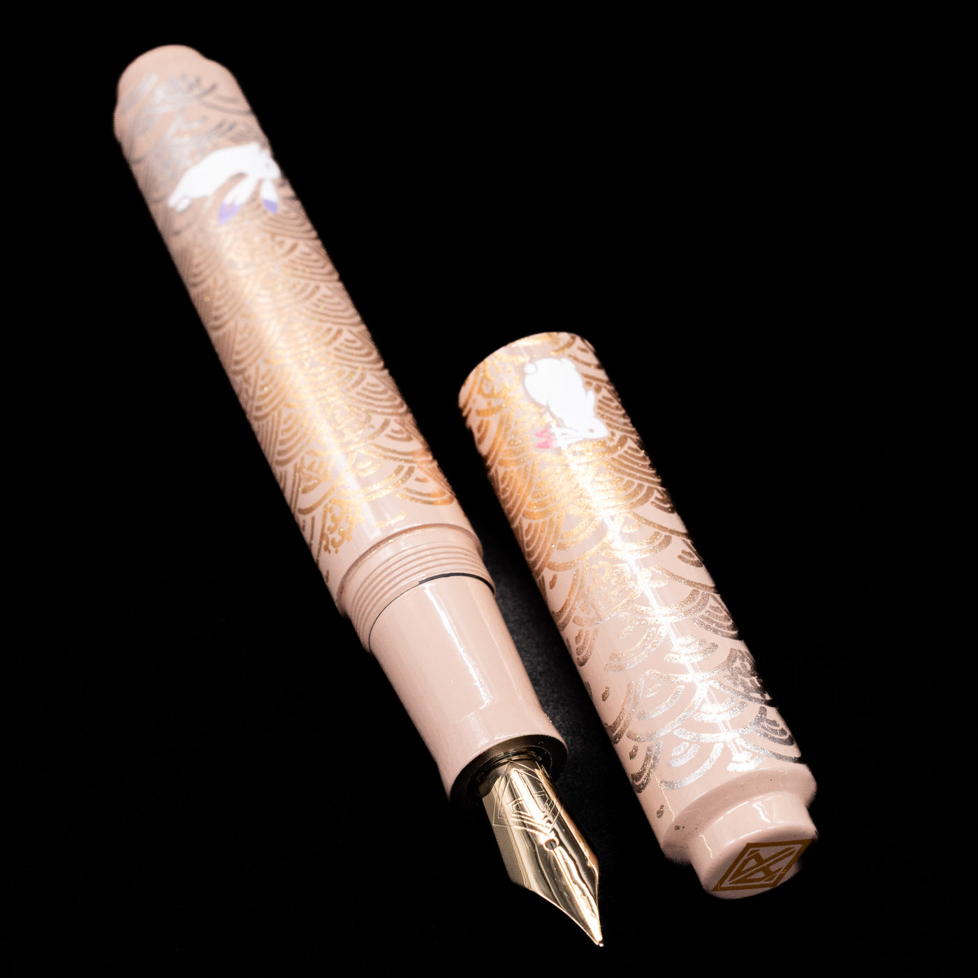A full view of the AP Limited Editions Sakura Lacquer Art Fountain Pen - Rabbits in a Summer Garden uncapped, with its cap laying next to the pen. 
