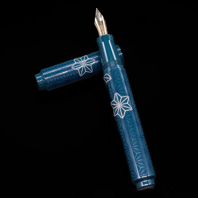 NAME laying on top of its cap in a crossed position showing full view of the entire uncapped pen.
