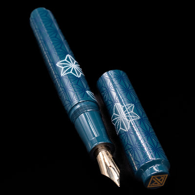  A full view of the AP Limited Editions Sakura Lacquer Art Fountain Pen - Snowflakes Blue uncapped, with its cap laying next to the pen.