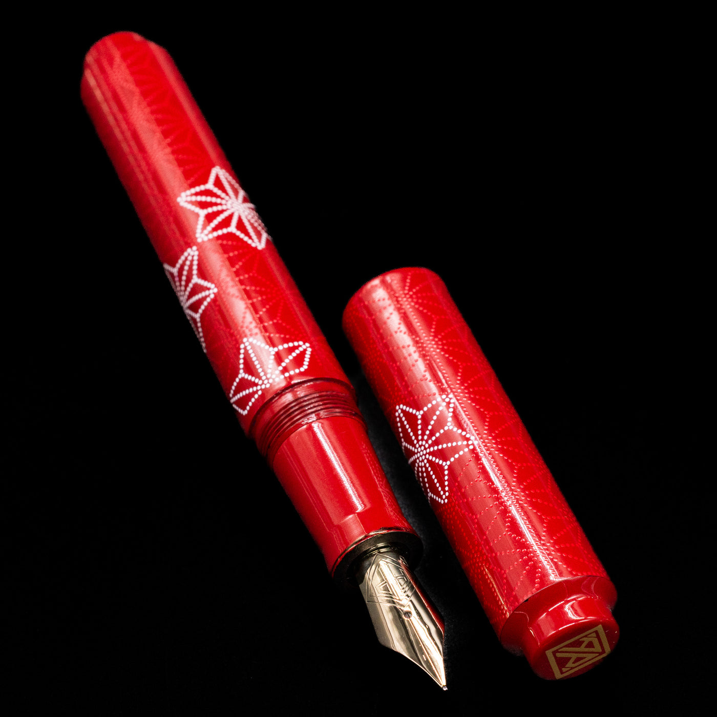  A full view of the AP Limited Editions Sakura Lacquer Art Fountain Pen - Snowflakes Red uncapped, with its cap laying next to the pen. 