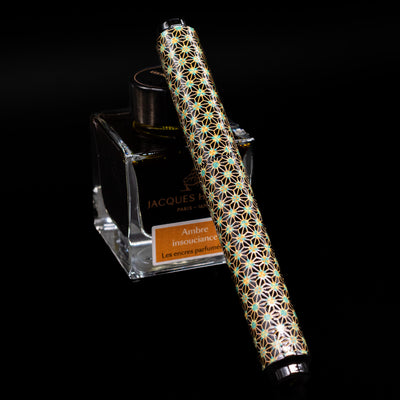 AP Limited Editions Sakura Lacquer Art Fountain Pen - Teal Stars capped, leaning against an ink bottle. 