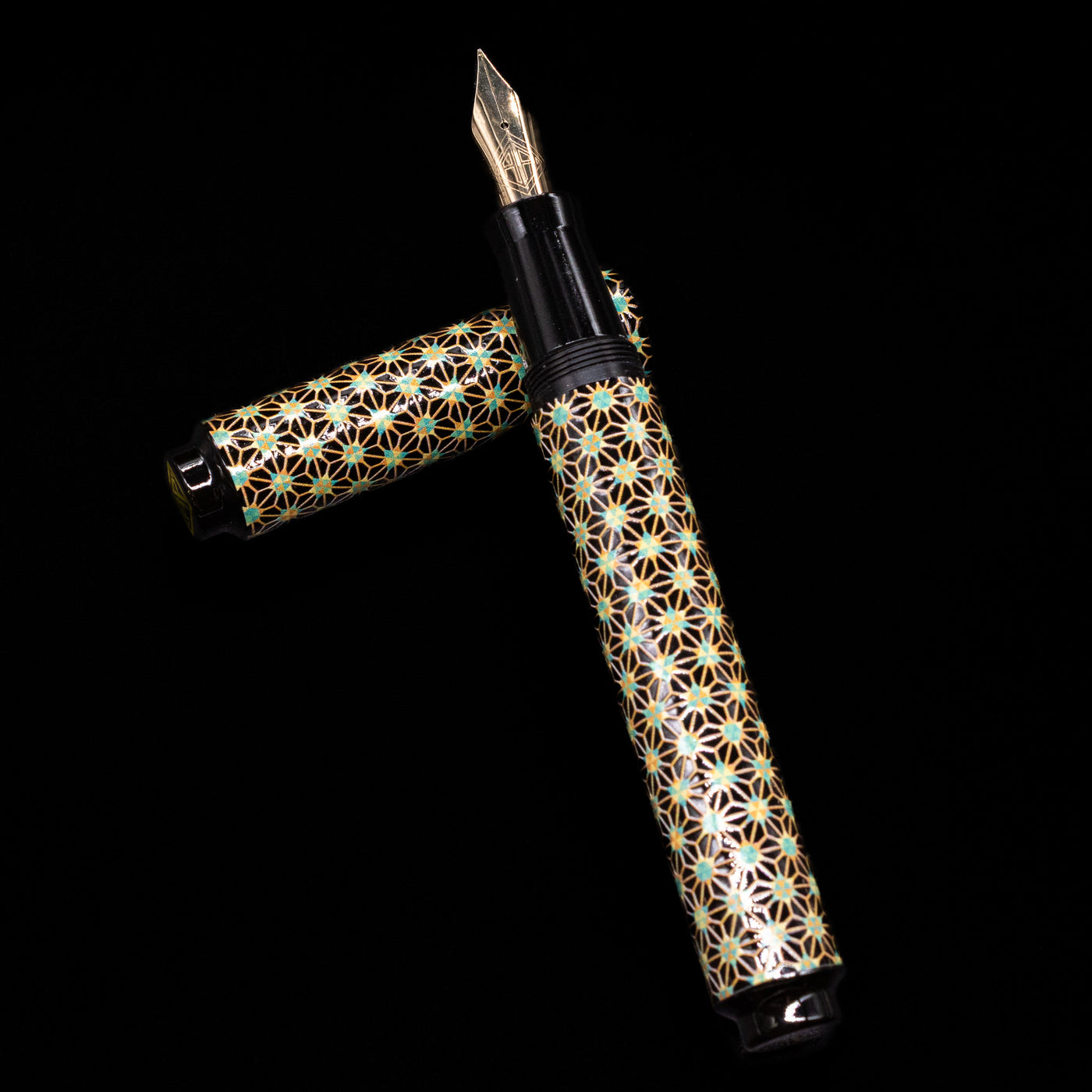 AP Limited Editions Sakura Lacquer Art Fountain Pen - Teal Stars laying on top of its cap in a crossed position showing full view of the entire uncapped pen.