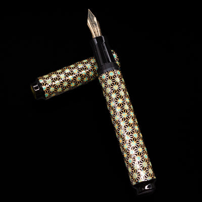 AP Limited Editions Sakura Lacquer Art Fountain Pen - Teal Stars laying on top of its cap in a crossed position showing full view of the entire uncapped pen.