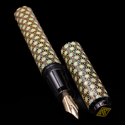  A full view of the AP Limited Editions Sakura Lacquer Art Fountain Pen - Teal Stars uncapped, with its cap laying next to the pen. 