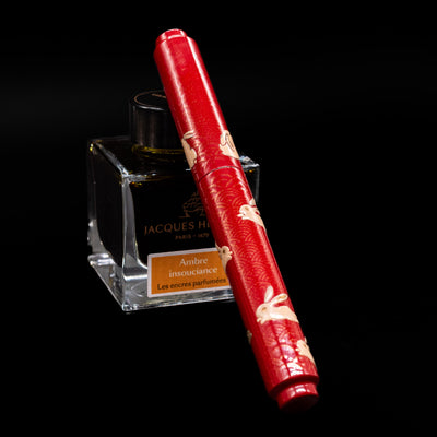 AP Limited Editions Sakura Lacquer Art Fountain Pen - Year of the Rabbit capped, leaning against an ink bottle. 
