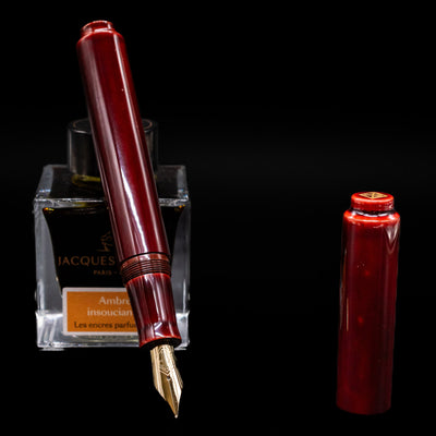 AP Limited Editions Urushi Lacquer Art Fountain Pen - Aka Tamenuri leaning on an ink bottle uncapped showcasing the detailing on the nib.
