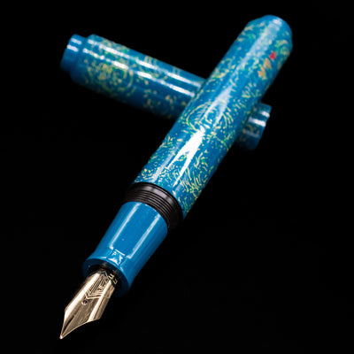 AP Limited Editions Urushi Lacquer Art Fountain Pen - Blue Bliss laying across its own cap, crossed, with a focus on the nib.