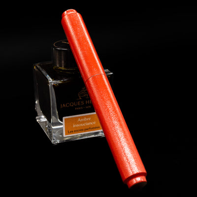AP Limited Editions Urushi Lacquer Art Fountain Pen - Colors of the Cosmos Aldebaran capped, leaning against an ink bottle. 