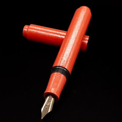 AP Limited Editions Urushi Lacquer Art Fountain Pen - Colors of the Cosmos Aldebaran laying across its own cap, crossed, with a focus on the nib.
