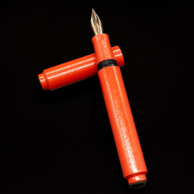 AP Limited Editions Urushi Lacquer Art Fountain Pen - Colors of the Cosmos Aldebaran laying on top of its cap in a crossed position showing full view of the entire uncapped pen.