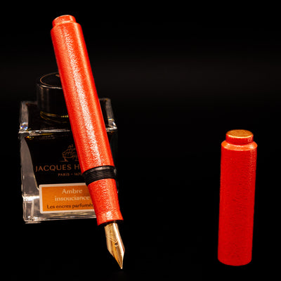 AP Limited Editions Urushi Lacquer Art Fountain Pen - Colors of the Cosmos Aldebaran leaning on an ink bottle uncapped showcasing the detailing on the nib.