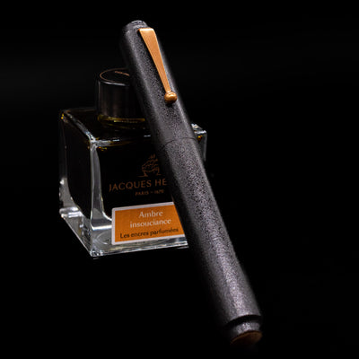 AP Limited Editions Urushi Lacquer Art Fountain Pen - Ishiji Black & Gold  capped, leaning against an ink bottle.