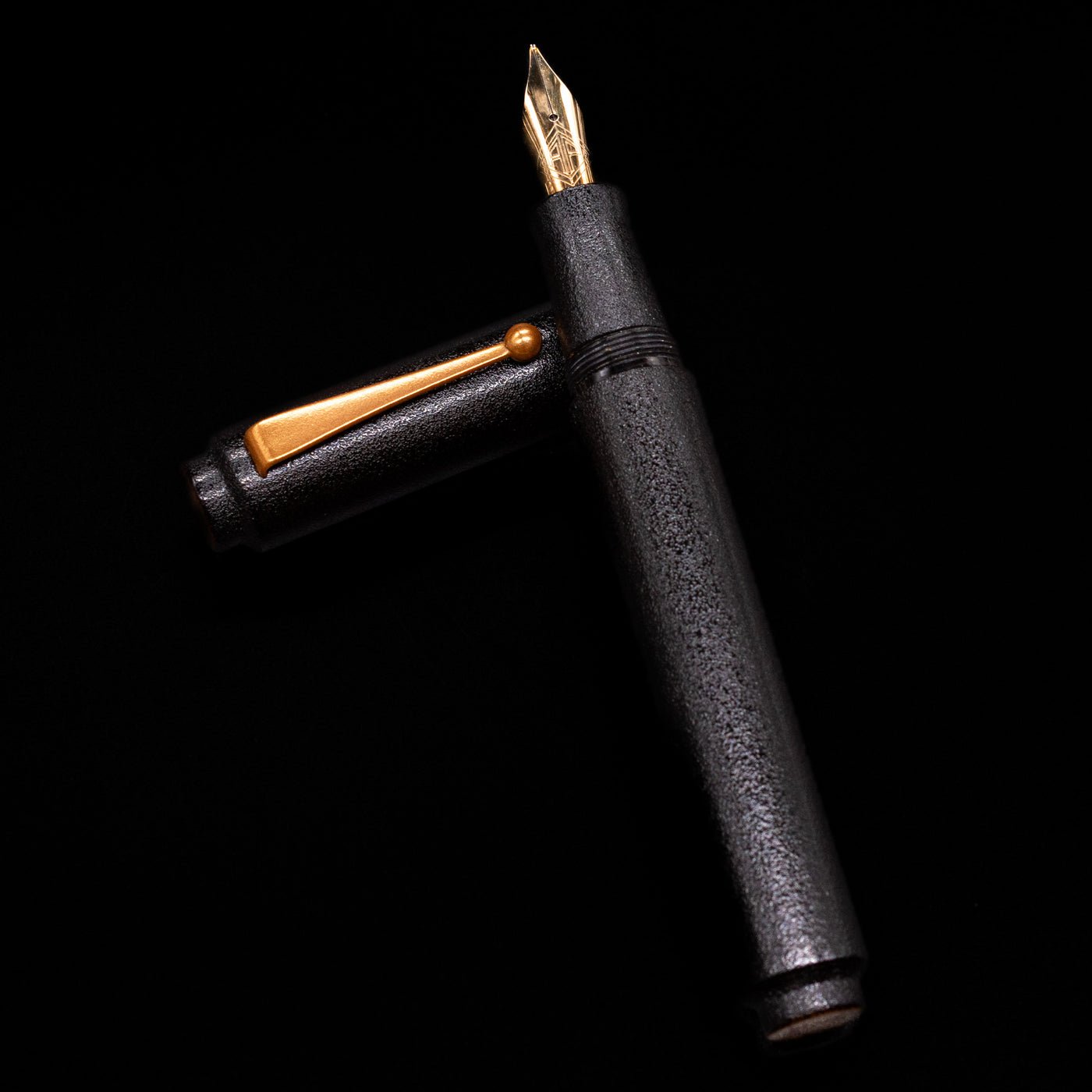 AP Limited Editions Urushi Lacquer Art Fountain Pen - Ishiji Black & Gold  laying on top of its cap in a crossed position showing full view of the entire uncapped pen.