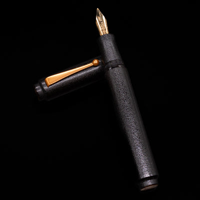 AP Limited Editions Urushi Lacquer Art Fountain Pen - Ishiji Black & Gold  laying on top of its cap in a crossed position showing full view of the entire uncapped pen.