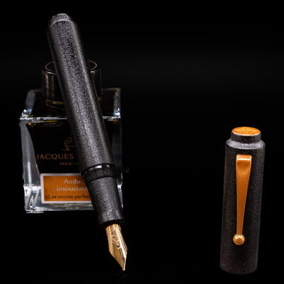 AP Limited Editions Urushi Lacquer Art Fountain Pen - Ishiji Black & Gold leaning on an ink bottle uncapped showcasing the detailing on the nib.