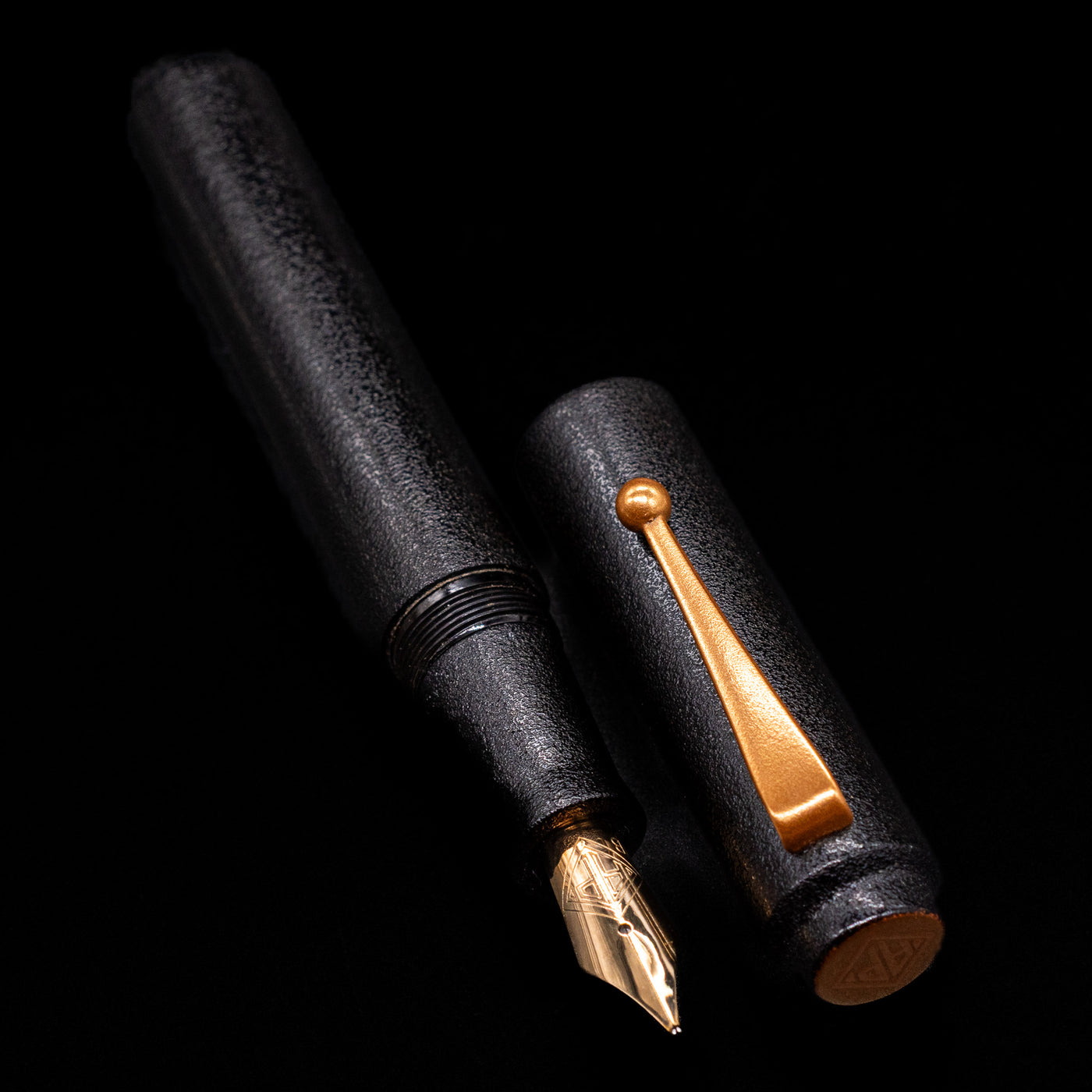 A full view of the AP Limited Editions Urushi Lacquer Art Fountain Pen - Ishiji Black & Gold uncapped, with its cap laying next to the pen. 