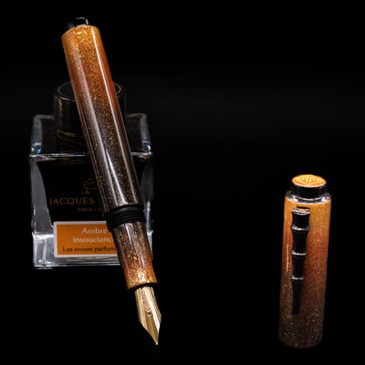 AP Limited Editions Urushi Lacquer Art Fountain Pen - Kinsaji (Black Bamboo Clip) leaning on an ink bottle uncapped showcasing the detailing on the nib.