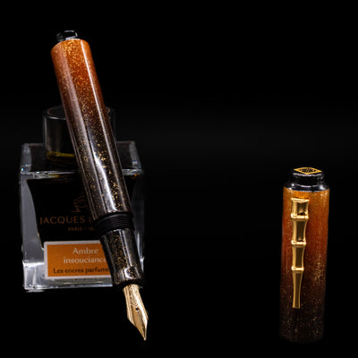 AP Limited Editions Urushi Lacquer Art Fountain Pen - Kinsaji (Gold Bamboo Clip) leaning on an ink bottle uncapped showcasing the detailing on the nib.