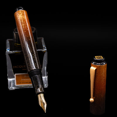 AP Limited Editions Urushi Lacquer Art Fountain Pen - Kinsaji (Gold Smooth Clip) leaning on an ink bottle uncapped showcasing the detailing on the nib.