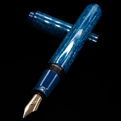 AP Limited Editions Urushi Lacquer Art Fountain Pen - Midnight laying across its own cap, crossed, with a focus on the nib.