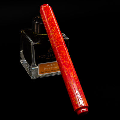 AP Limited Editions Urushi Lacquer Art Fountain Pen - Red Earth capped, leaning against an ink bottle. 