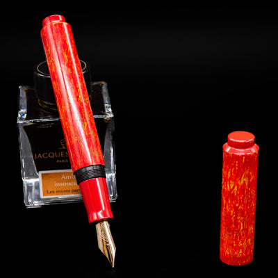 AP Limited Editions Urushi Lacquer Art Fountain Pen - Red Earth leaning on an ink bottle uncapped showcasing the detailing on the nib.