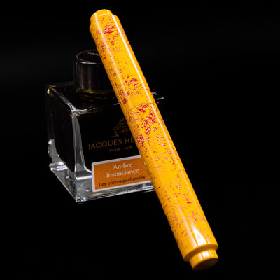 AP Limited Editions Urushi Lacquer Art Fountain Pen - Sunshine capped, leaning against an ink bottle. 