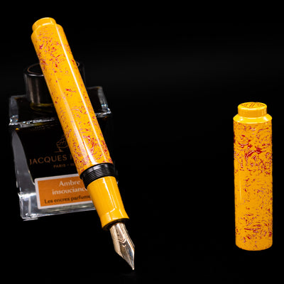 AP Limited Editions Urushi Lacquer Art Fountain Pen - Sunshine leaning on an ink bottle uncapped showcasing the detailing on the nib.