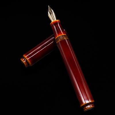AP Limited Editions Urushi Lacquer Art Fountain Pen - Tamenuri Yellow laying across its own cap, crossed, with a focus on the nib.