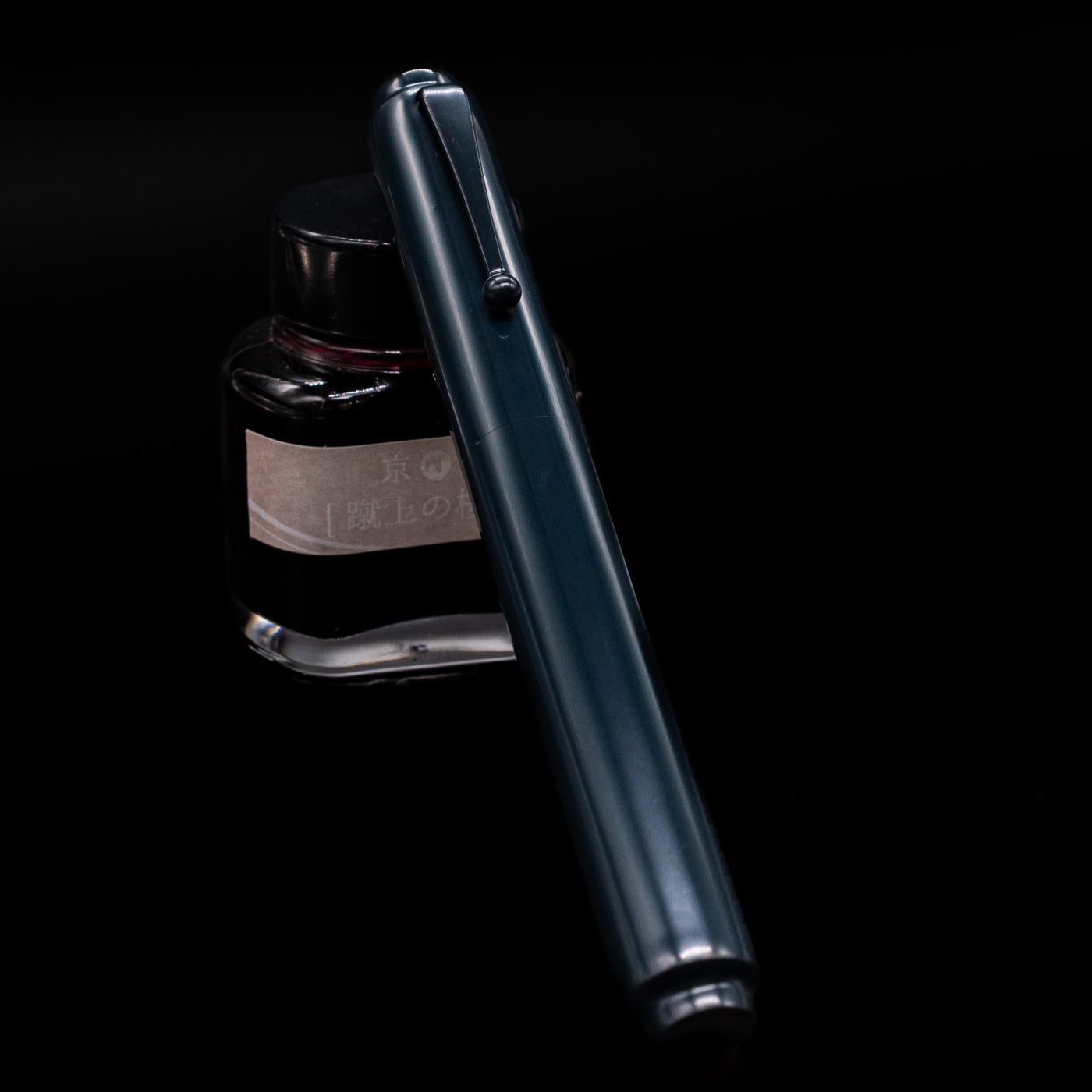 AP Limited Editions Urushi Lacquer Art Fountain Pen - Tetsu-Kon capped, leaning against an ink bottle. 