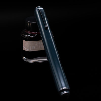 AP Limited Editions Urushi Lacquer Art Fountain Pen - Tetsu-Kon capped, leaning against an ink bottle. 