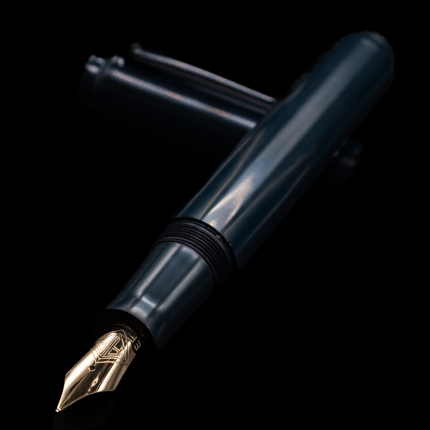 AP Limited Editions Urushi Lacquer Art Fountain Pen - Tetsu-Kon laying across its own cap, crossed, with a focus on the nib.