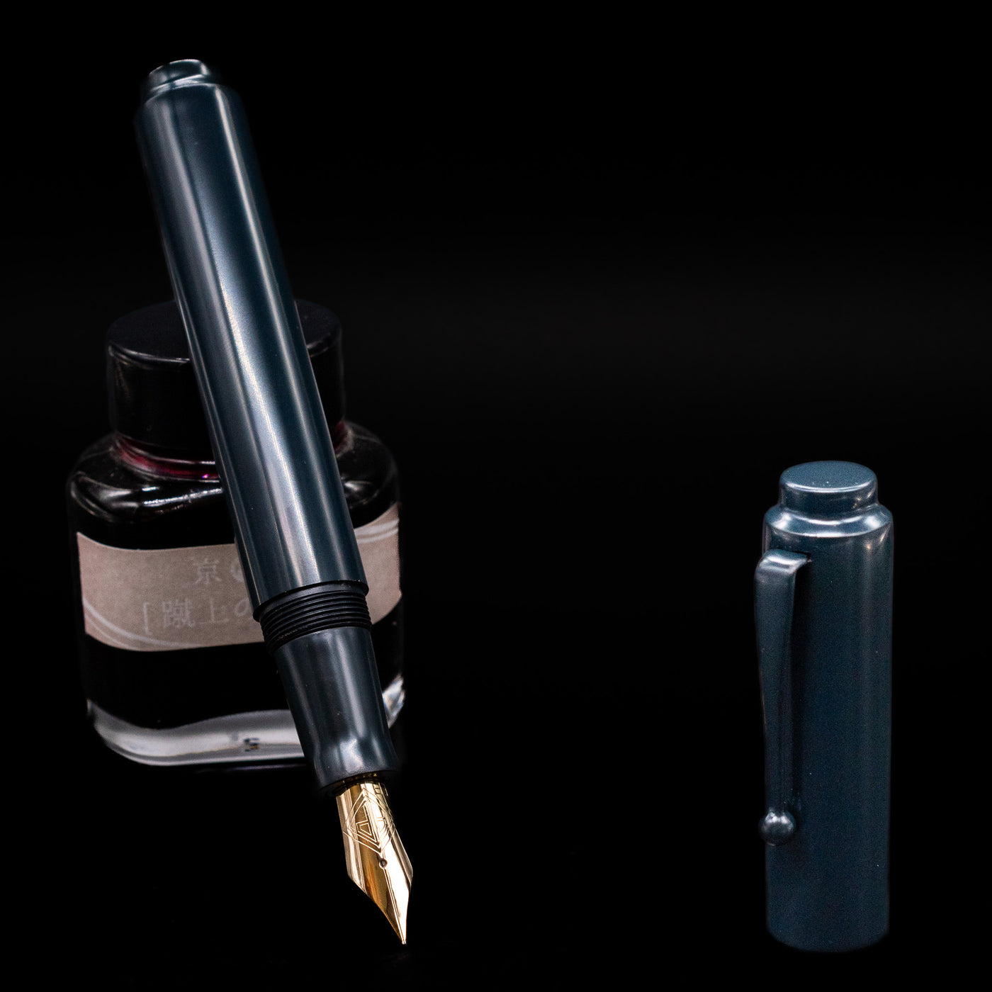 AP Limited Editions Urushi Lacquer Art Fountain Pen - Tetsu-Kon leaning on an ink bottle uncapped showcasing the detailing on the nib.