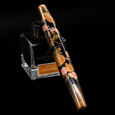 AP Limited Editions Writer Maki-e Fountain Pen - Chrystanthemum (Prototype) capped, leaning against an ink bottle. 