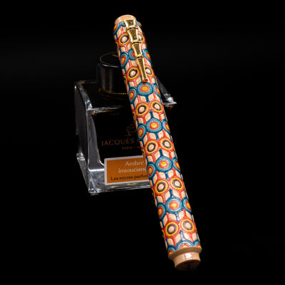 AP Limited Editions Writer Maki-e Fountain Pen - Orbit capped, leaning against an ink bottle. 