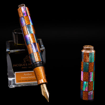 AP Limited Editions Writer Maki-e Fountain Pen - Sparkle leaning on an ink bottle uncapped showcasing the detailing on the nib.