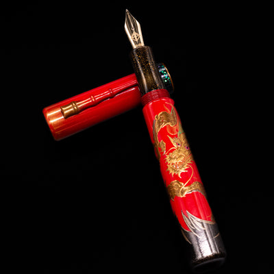AP Limited Editions Writer Maki-e Fountain Pen - The Celebrated Dragon laying on top of its cap in a crossed position showing full view of the entire uncapped pen.