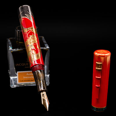 AP Limited Editions Writer Maki-e Fountain Pen - The Celebrated Dragon leaning on an ink bottle uncapped showcasing the detailing on the nib.