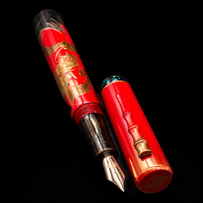 A full view of the AP Limited Editions Writer Maki-e Fountain Pen - The Celebrated Dragon uncapped, with its cap laying next to the pen. 