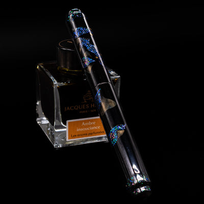 AP Limited Editions Writer Maki-e Fountain Pen - The Firefly Squid capped, leaning against an ink bottle. 